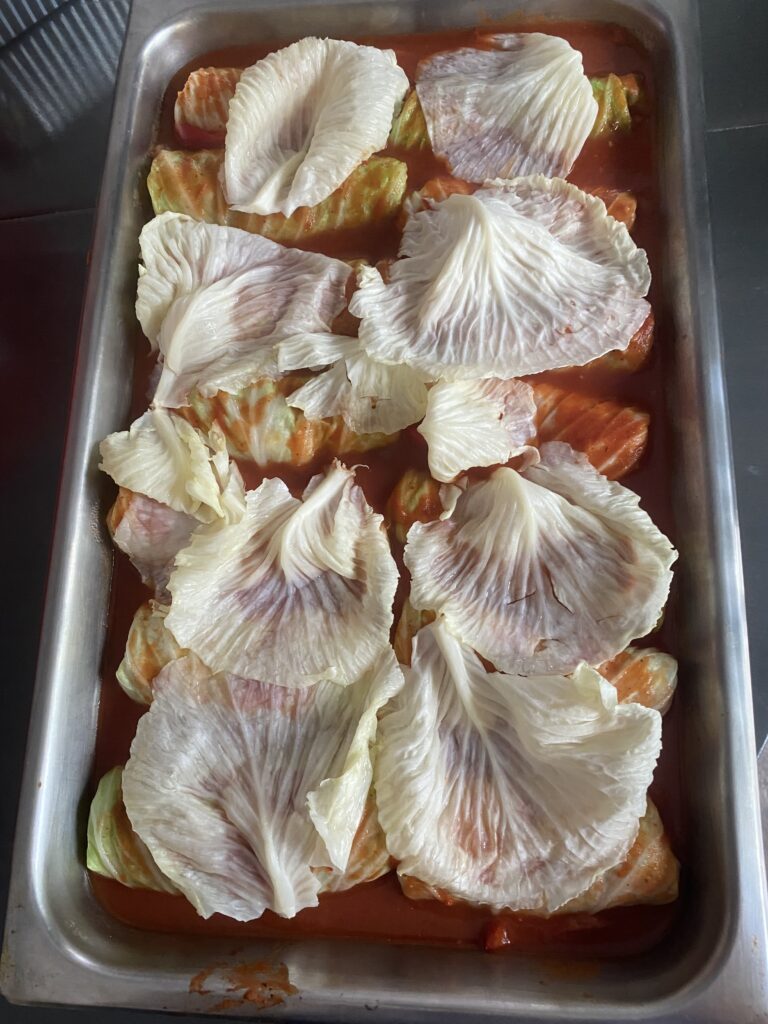 Cabbage rolls covered with extra cabbage leaves in a baking pan before baking